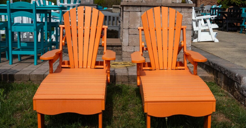 Two bright orange lounge chairs on a grassy area